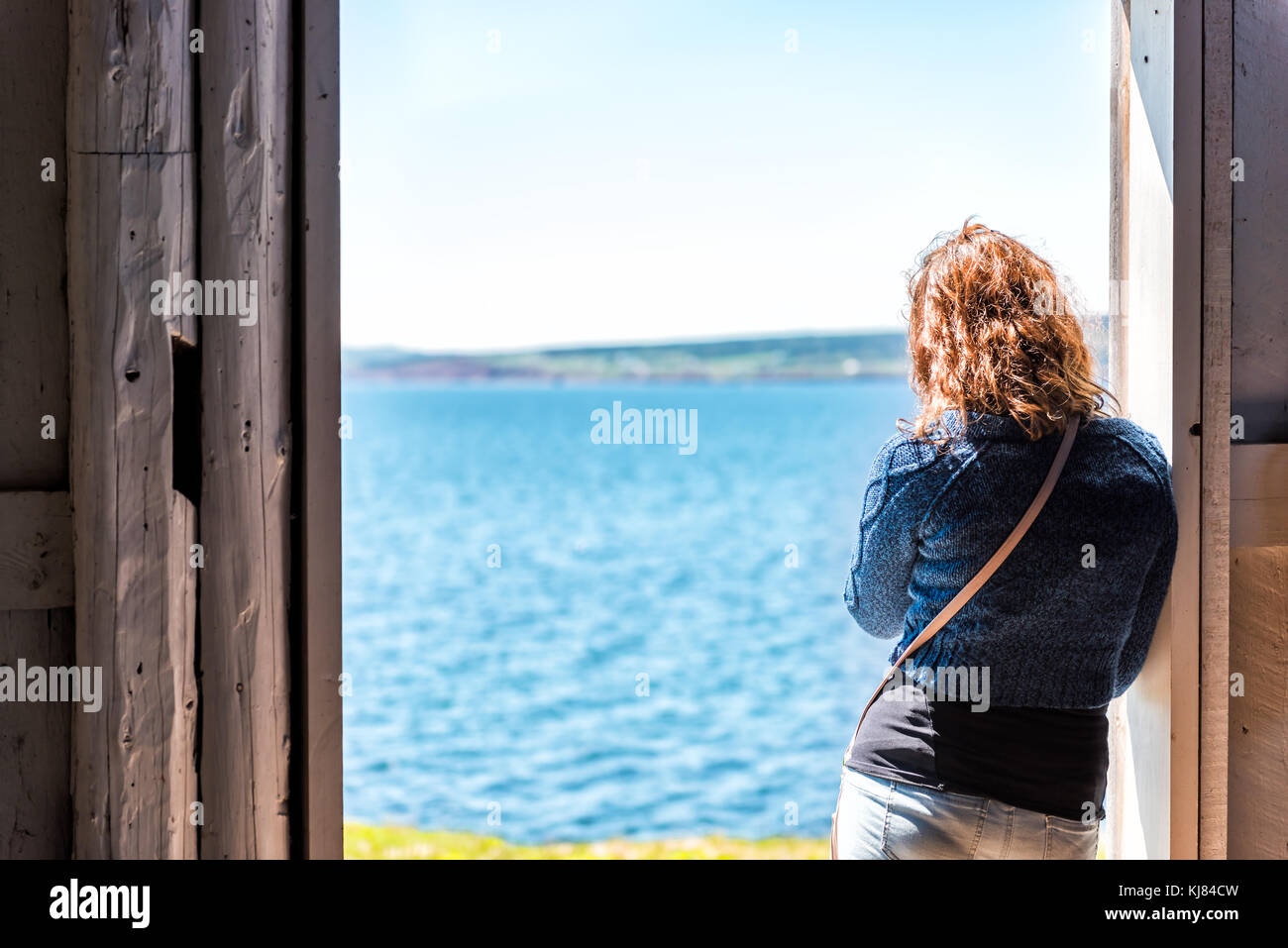 Vue arrière d'un seul, seul, jeune femme aux cheveux rouges l'article entrée par porte ouverte à la nature de l'océan Pacifique en vue, falaise, côte en ru Banque D'Images