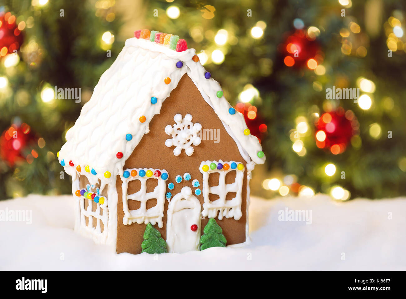 Noël fait maison Gingerbread House dans la neige. Décoration arbre de Noël dans l'arrière-plan. Banque D'Images