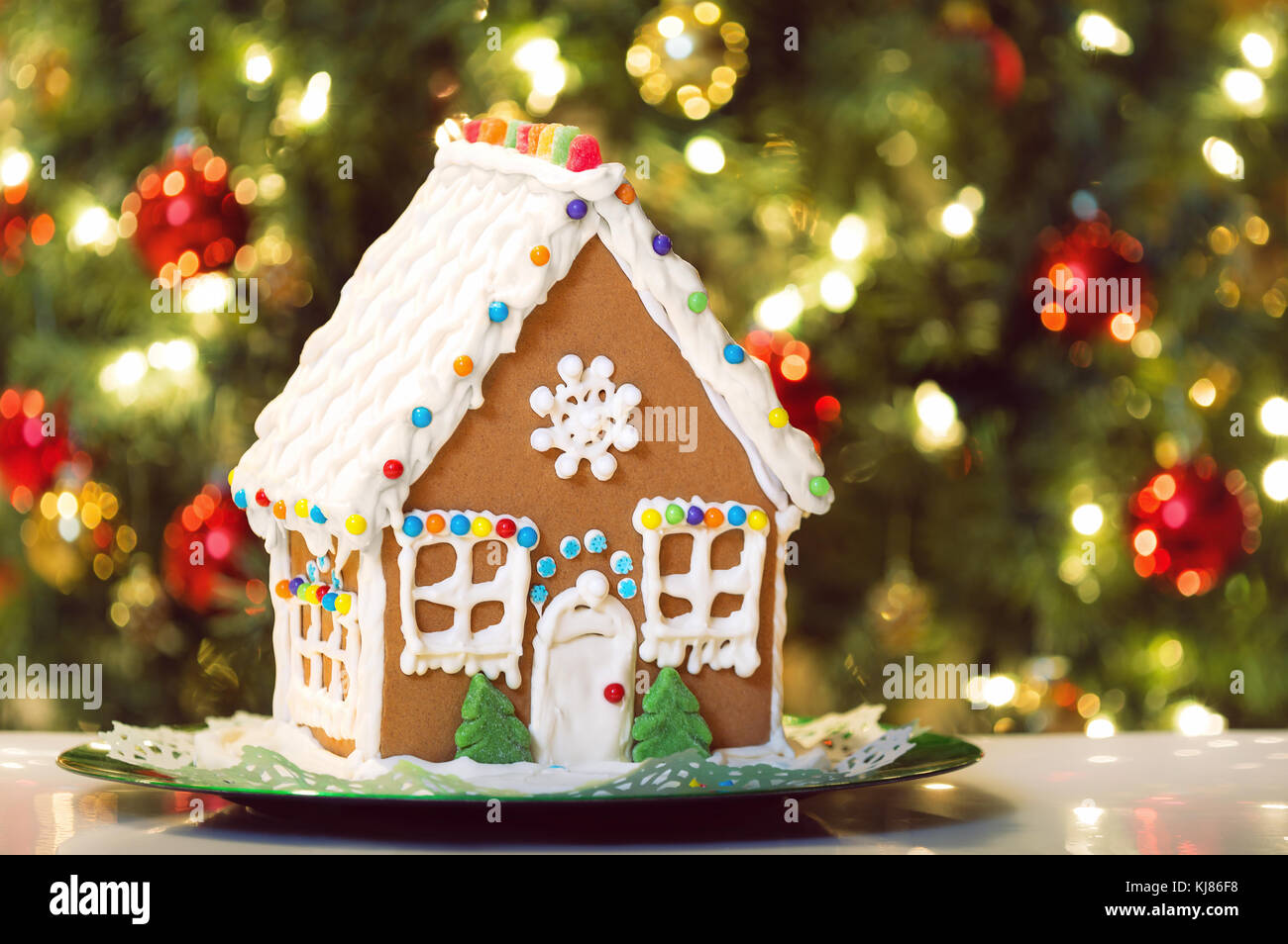 Noël fait maison gingerbread house affiche sur une table. Décoration arbre de Noël dans l'arrière-plan. Banque D'Images