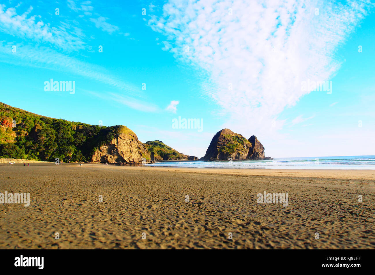 Scenic coucher du soleil à Piha beach avec des formations rocheuses à l'arrière-plan Banque D'Images