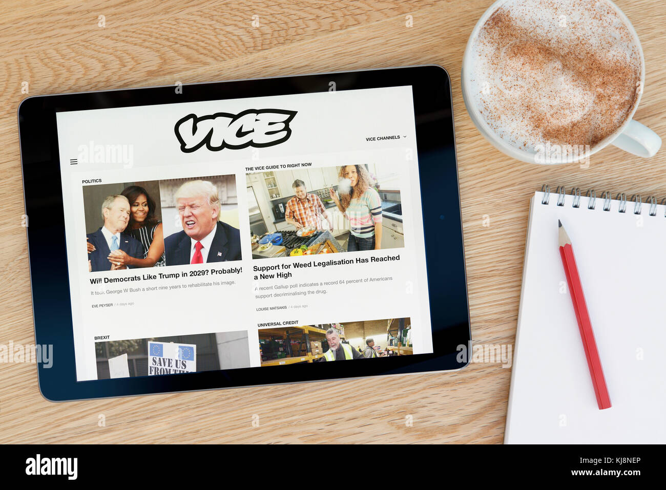 Le site web dispose d'un vice sur tablette iPad dispositif qui repose sur une table en bois à côté d'un bloc-notes et un crayon et une tasse de café (rédaction uniquement) Banque D'Images