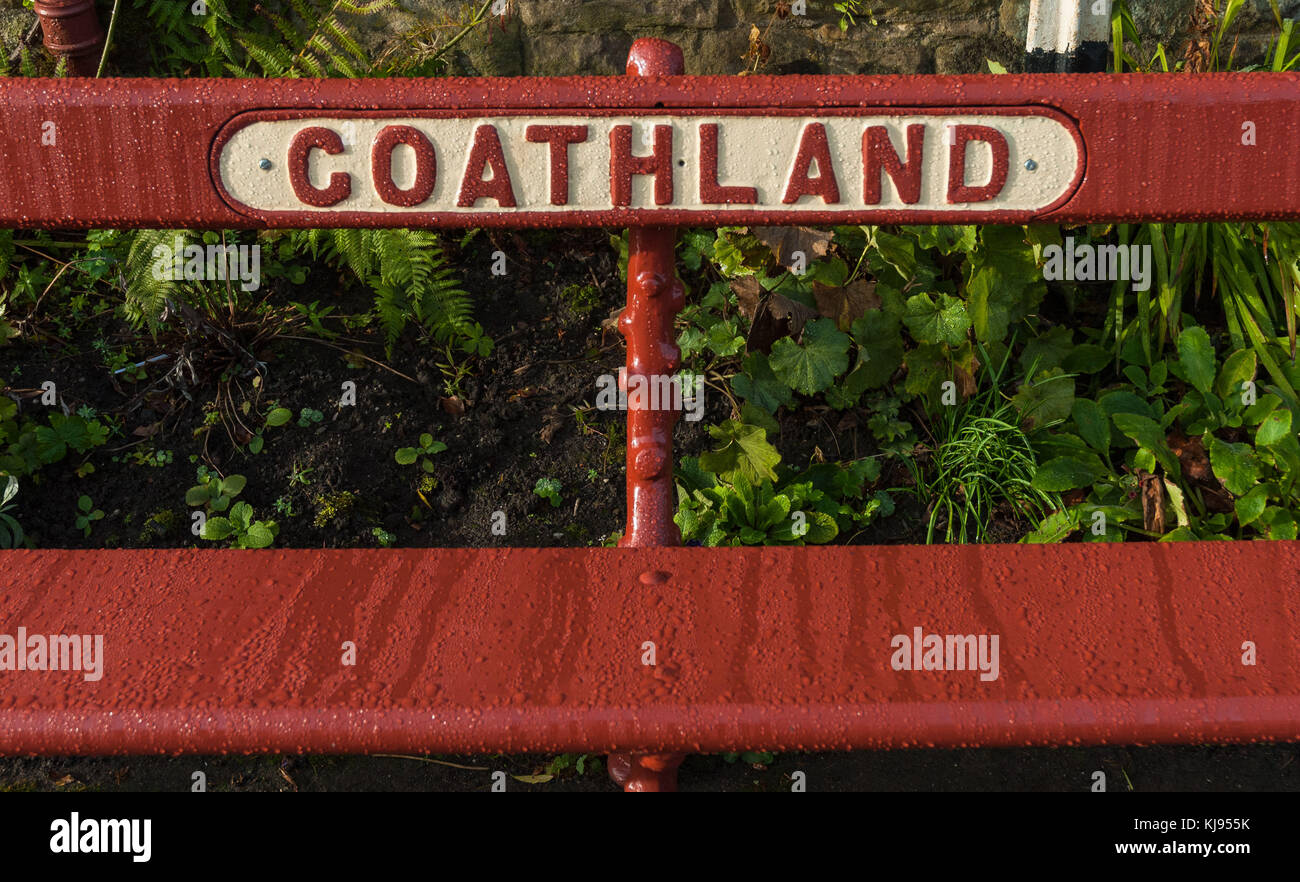 Un banc de fer vintage rouge à Goathland Station, North Yorkshire. Banque D'Images