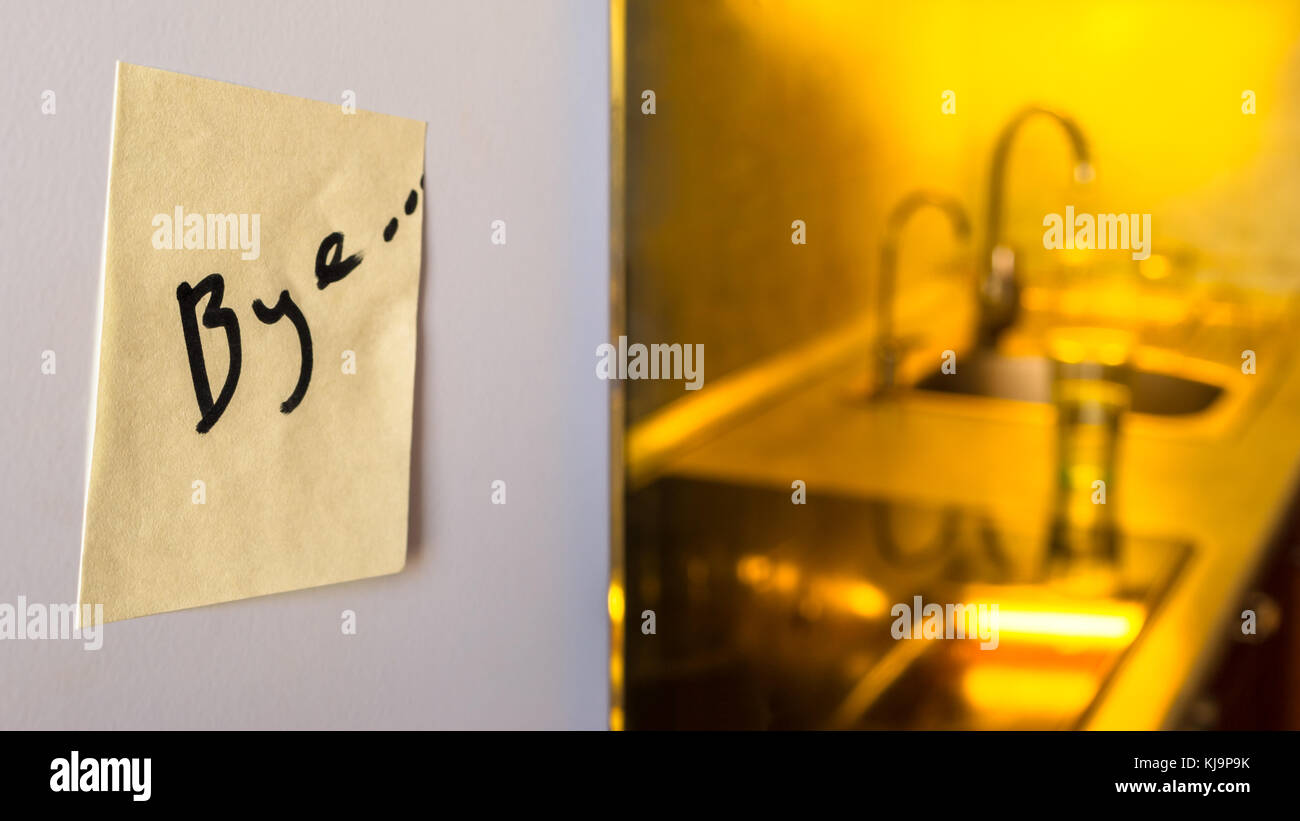 Fin de la relation concept : au revoir un note sur un réfrigérateur avec des appareils de cuisine et les voyants jaunes en arrière-plan flou Banque D'Images