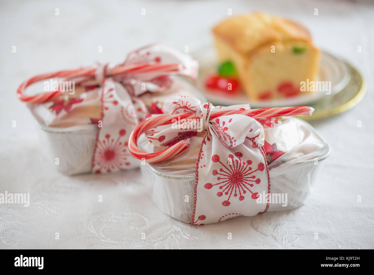 Cadeau enveloppé de Noël avec des arcs et un gâteau aux fruits Banque D'Images
