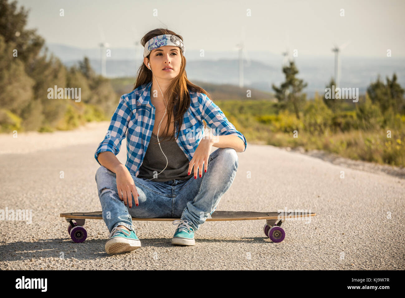 Belle jeune femme assise sur une planche à roulettes Banque D'Images