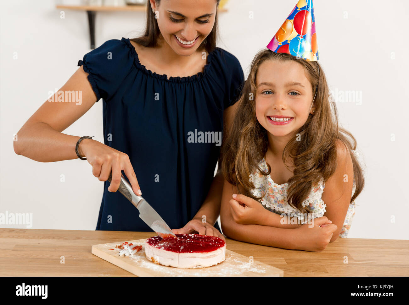 Tourné d'une mère et sa fille cuting la coupe du gâteau anniversaire Banque D'Images