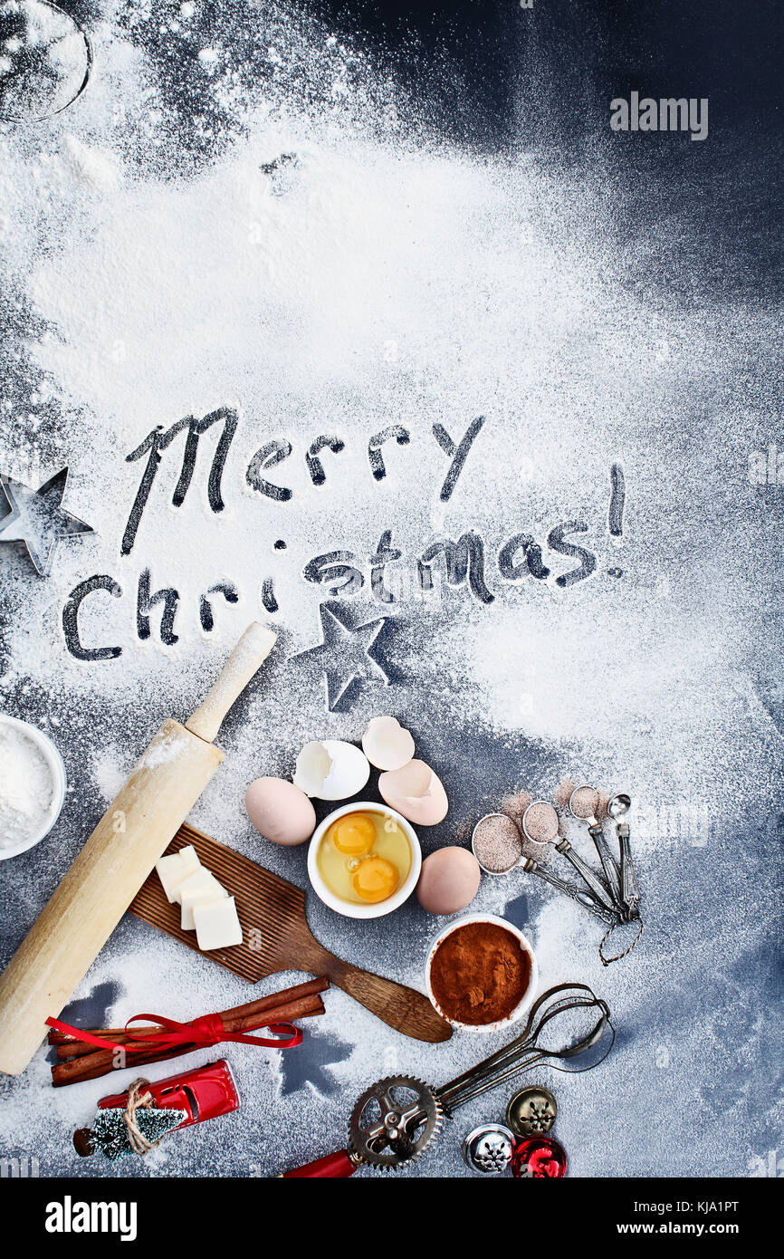 Rouleau à pâtisserie en bois avec les ingrédients et ustensiles de cuisine pâtisserie située sur un fond poudré de farine qui se lit "Joyeux Noël !" libre shot bof Banque D'Images