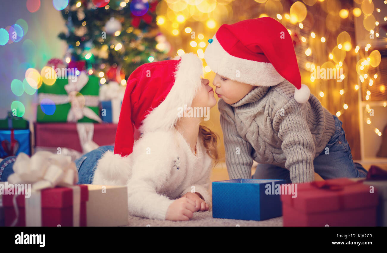 Garçon et fille se trouvant sur le plancher avec présente near Christmas Tree Banque D'Images