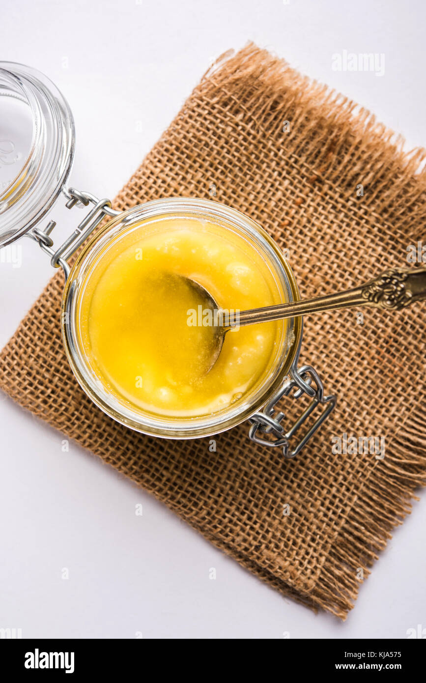 Le Desi ghee ou beurre clarifié en verre ou en céramique contenant du cuivre ou pot avec cuillère, selective focus Banque D'Images