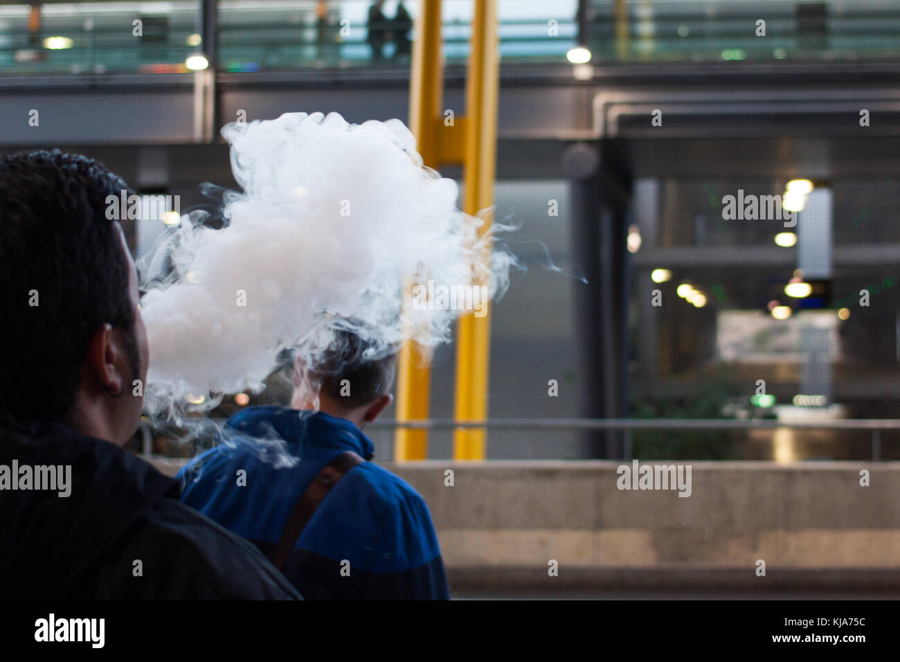 Silhouette homme fumer cigarette électronique et en soufflant un nuage de vapeur Banque D'Images