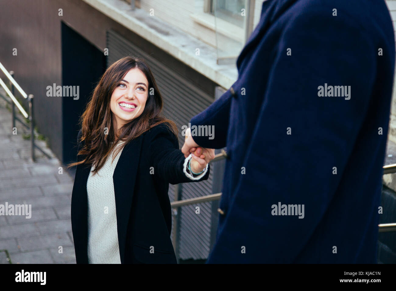 Belle et heureuse en amour couple holding hands en descendant les escaliers à l'extérieur Banque D'Images