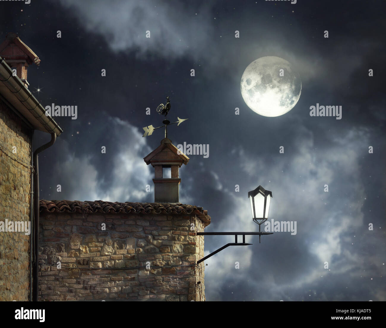 Meubles anciens toits avec girouette coq et cheminées dans un beau ciel de nuit avec la pleine lune et nuages Banque D'Images
