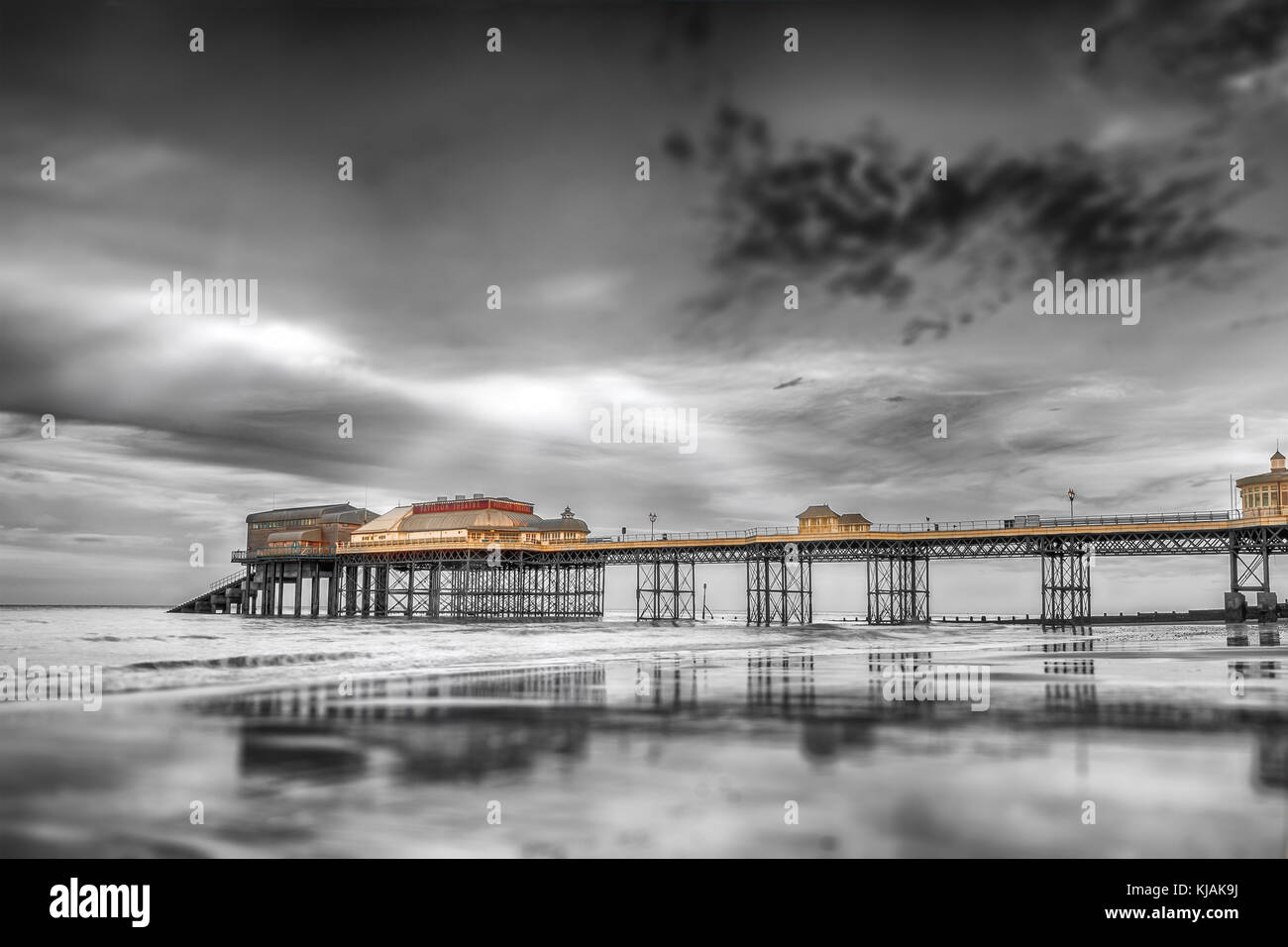 Jetée de Cromer norfolk historique reflétant dans la mer en noir et blanc. la lumière du soleil s'échapper les nuages et illumine la jetée en couleur. co spectaculaire Banque D'Images