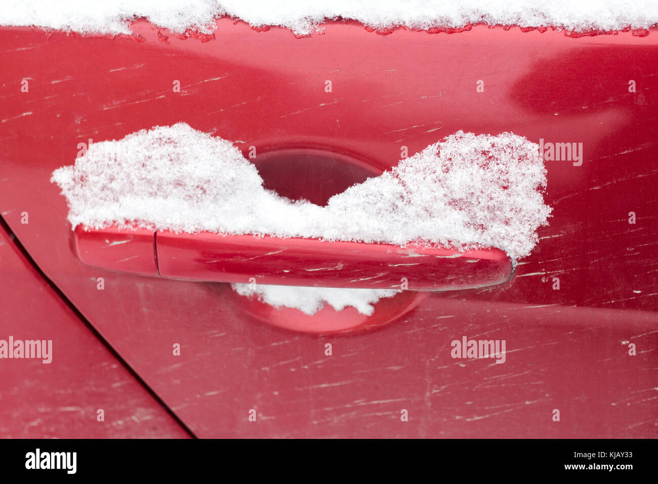 Poignée de porte de voiture rouge unique recouvert de neige fraîche. le verrou a été bloqué fermé. . Banque D'Images