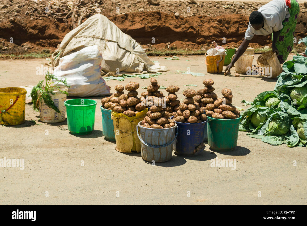 Seaux de pommes sur l'affichage à vendre au bord de la route avec femme africaine en arrière-plan, de travail au Kenya, Afrique de l'Est Banque D'Images