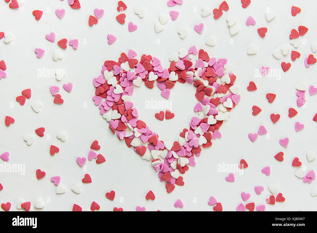 Coeur en multi-couleurs de paillettes de sucre bonbons éparpillés sur fond noir en blanc romantique Saint-Valentin anniversaire la charité. La fête des mères d'accueil. Banque D'Images