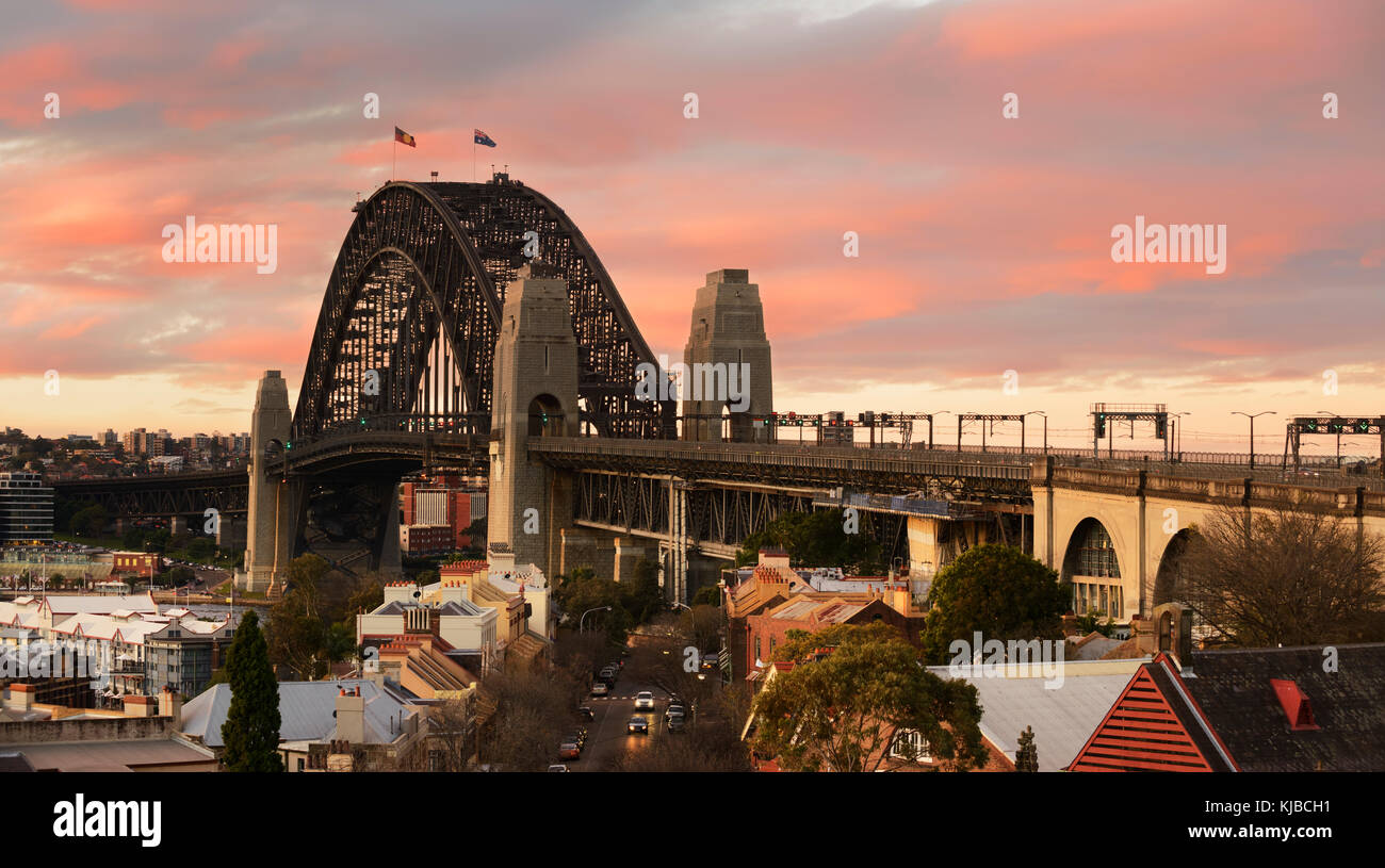 Image panoramique de la Sydney Harbour Bridge comme il a été vu de la colline de l'Observatoire au cours de jaune et rose spectaculaire coucher du soleil. Banque D'Images