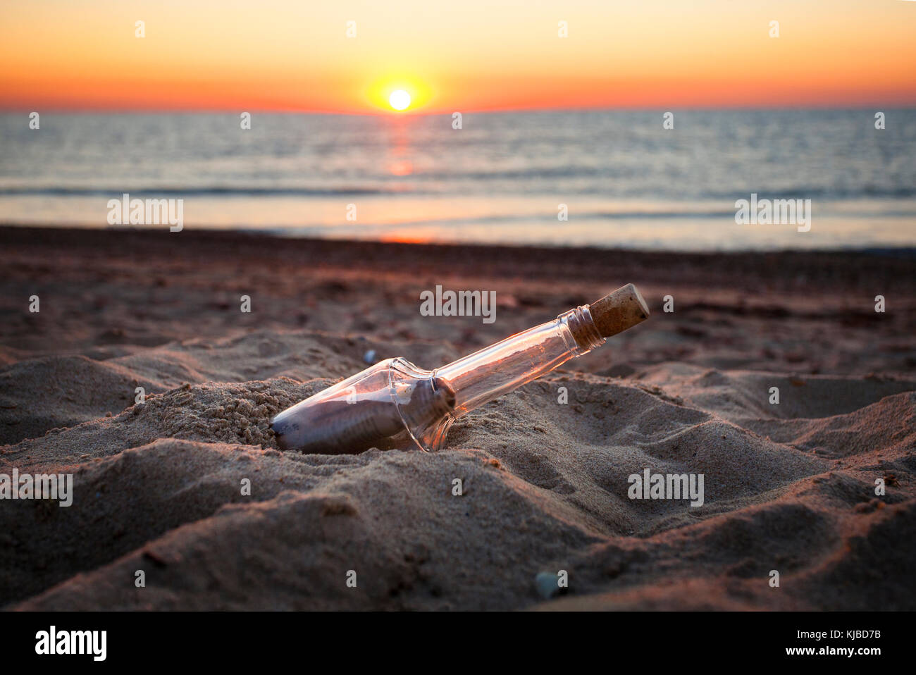 Message avec lettre à l'intérieur de la bouteille sur une plage au coucher du soleil Banque D'Images