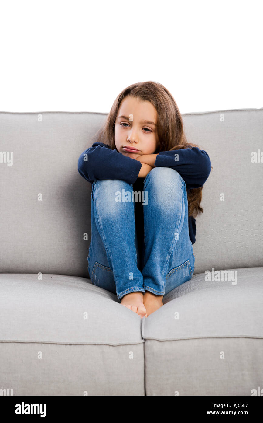 Petite fille assise sur un canapé et contrarié par quelque chose Banque D'Images