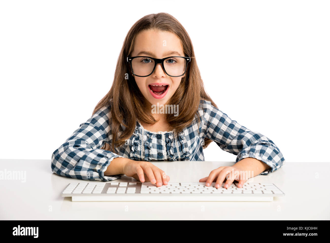 Petite fille assise sur un bureau et travailler avec un ordinateur Banque D'Images