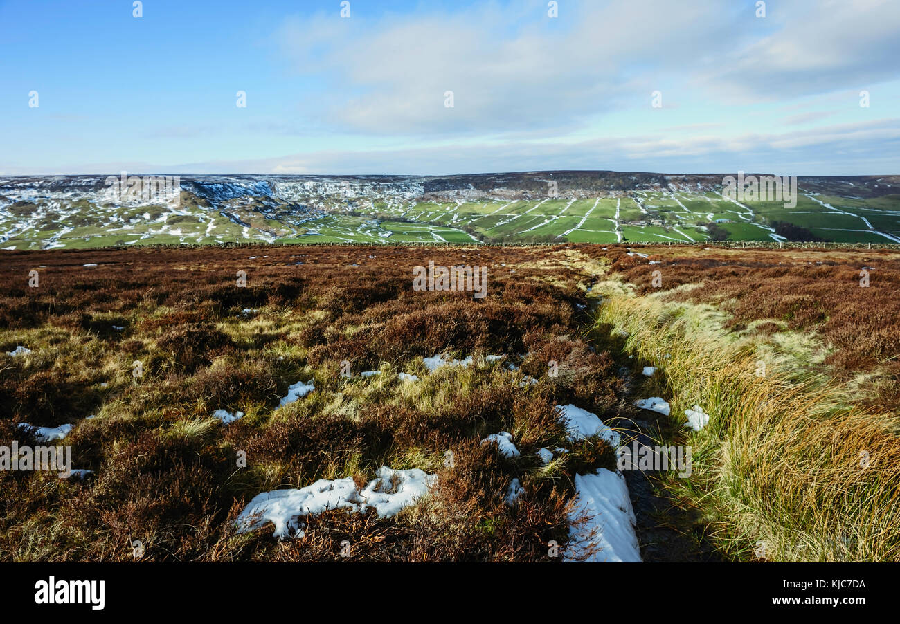 Plaques de neige au cours de la lande de bruyère dominé le North York Moors sur une belle matinée d'hiver flanquée de terres agricoles, Yorkshire, UK. Banque D'Images