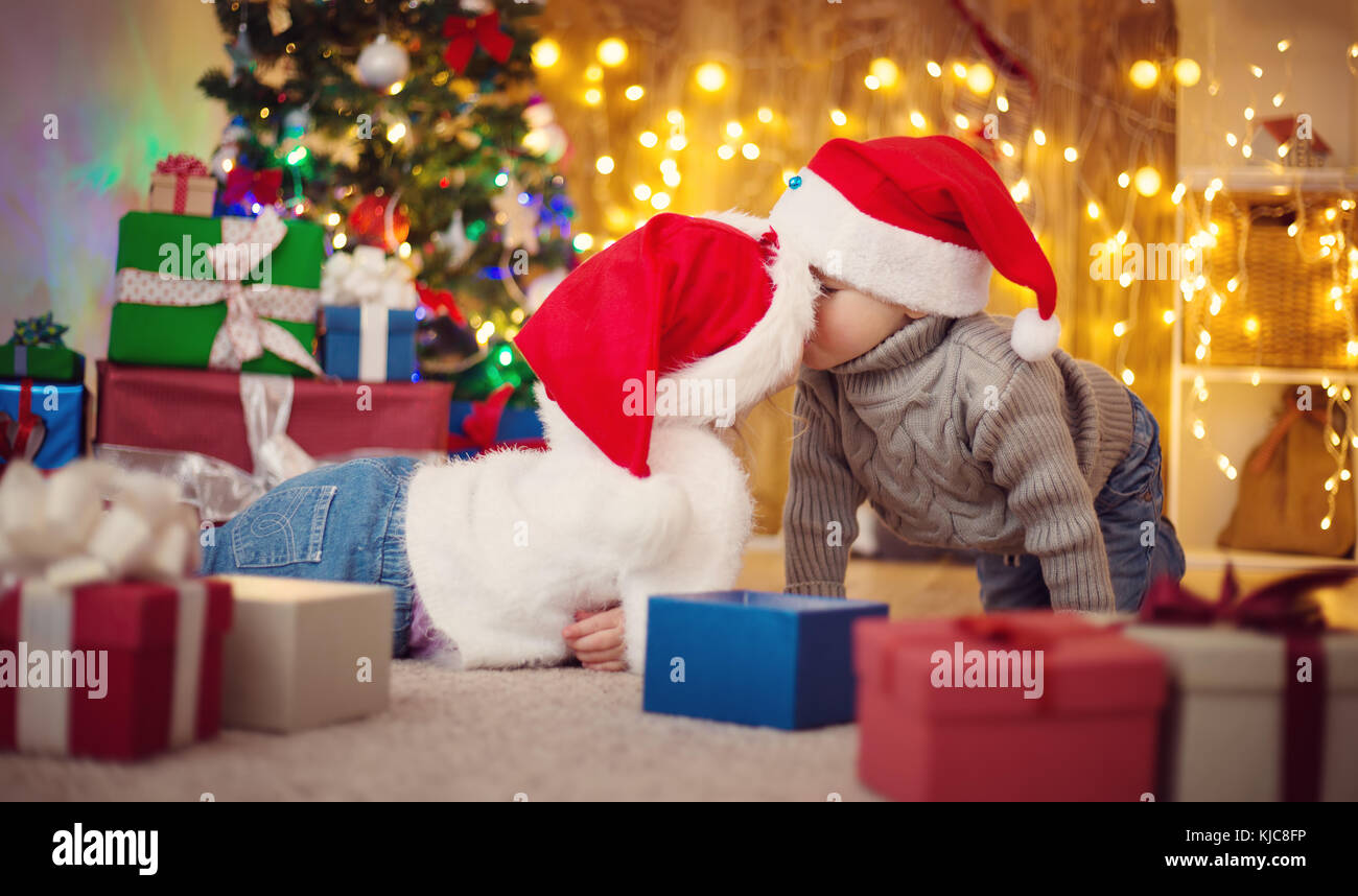 Garçon et fille se trouvant sur le plancher avec présente near Christmas Tree Banque D'Images