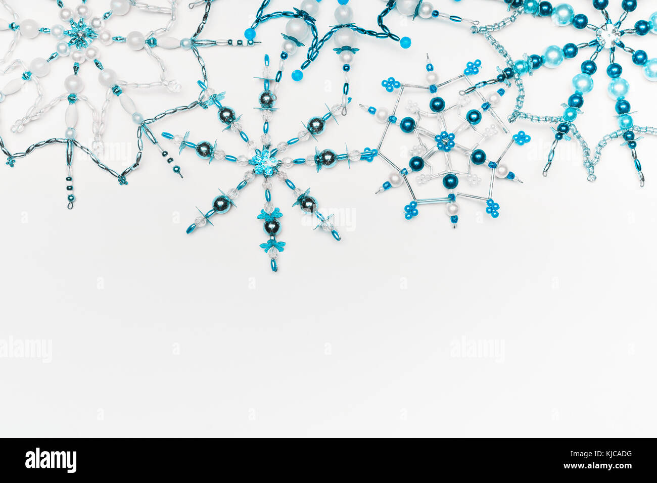 Concept d'hiver ou de noël. frontière de diverses handmade blue snowflakes fabriqués à partir de perles et bugle sur blanc 24 arrière-plan, Vue de dessus. Mise en page pour saluer Banque D'Images