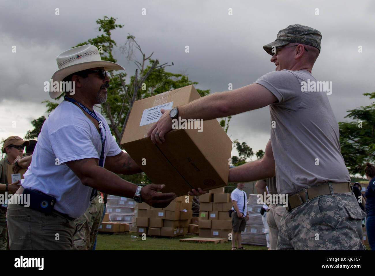 LOS LLANOS, Puerto Rico - Le Capitaine de l'ARMÉE AMÉRICAINE J. Scott Detweiler, commandant de la 172e Détachement des affaires publiques, des troupes de garnison, 86e Commandement Le commandement de la Garde nationale, Vermont, passe une boîte d'épicerie à un bénévole dans une église locale, le 14 novembre 2017. L'Agence fédérale de gestion des urgences, l'armée, Samaritan's Purse, et les volontaires locaux distribués courses pour 1 000 familles dans la région. (U.S. Photo de l'armée par le Sgt. Avery Cunningham) Banque D'Images