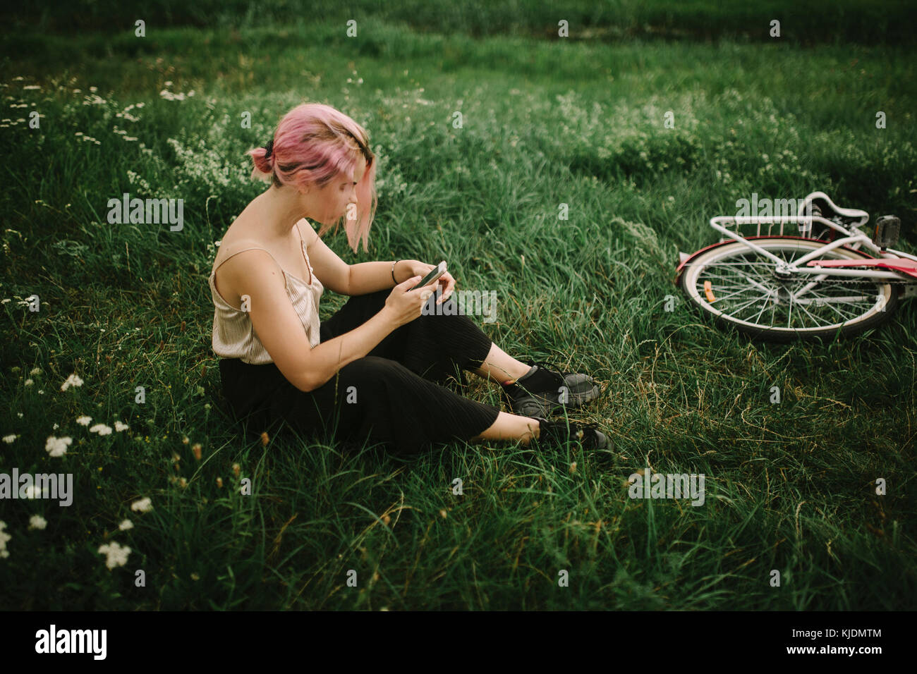 Caucasian woman sitting entrepiste texting on cell phone Banque D'Images