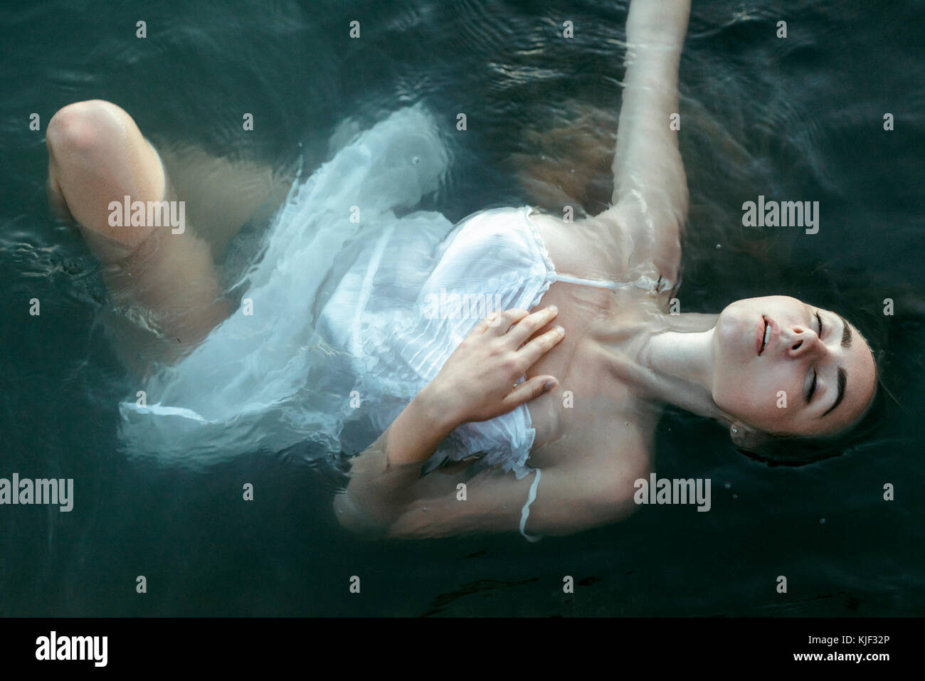 Caucasian woman wearing a dress floating in water Banque D'Images