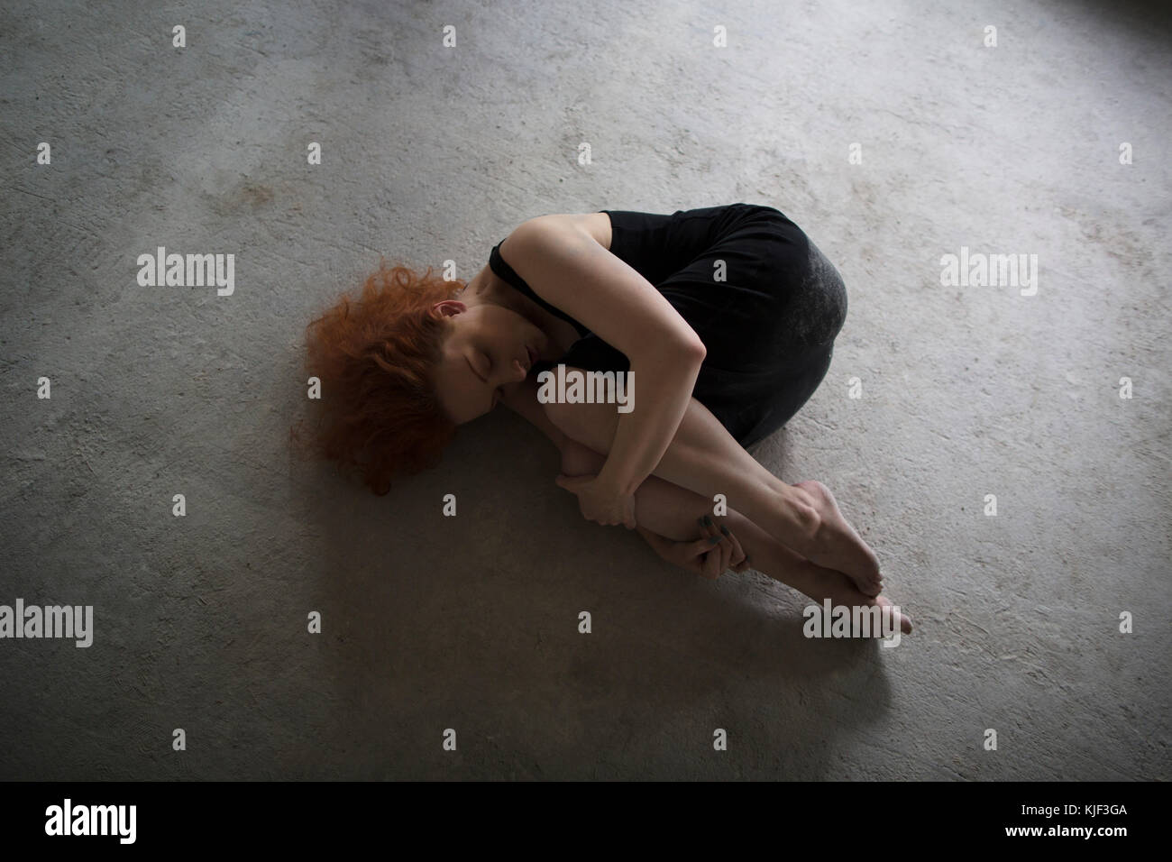 Caucasian woman béton en position fœtale Banque D'Images