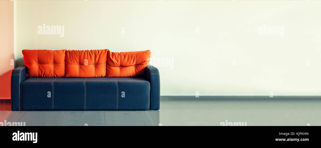Canapé, design d'intérieur, bureau. Salle d'attente vide avec un canapé bleu moderne avec coussins jaune en face de la porte et une horloge sur le mur de savs. Banque D'Images