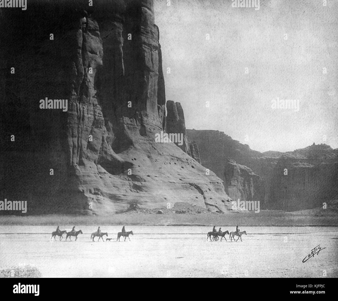 Photographie d'un groupe d'hommes amérindiens à cheval dans le désert, devant le Canyon de Chelly, intitulée 'Canyon de Chelly (prononcé de Shay)', par Edward S Curtis, Arizona, 1904. De la Bibliothèque publique de New York. Banque D'Images