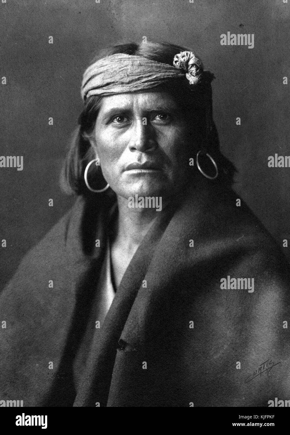Photographie d'un chef Hopi, portant de grandes boucles d'oreilles, un bandeau et un gros jet sur ses épaules, photographie d'Edward S. Curtis, 1903. De la Bibliothèque publique de New York. Banque D'Images