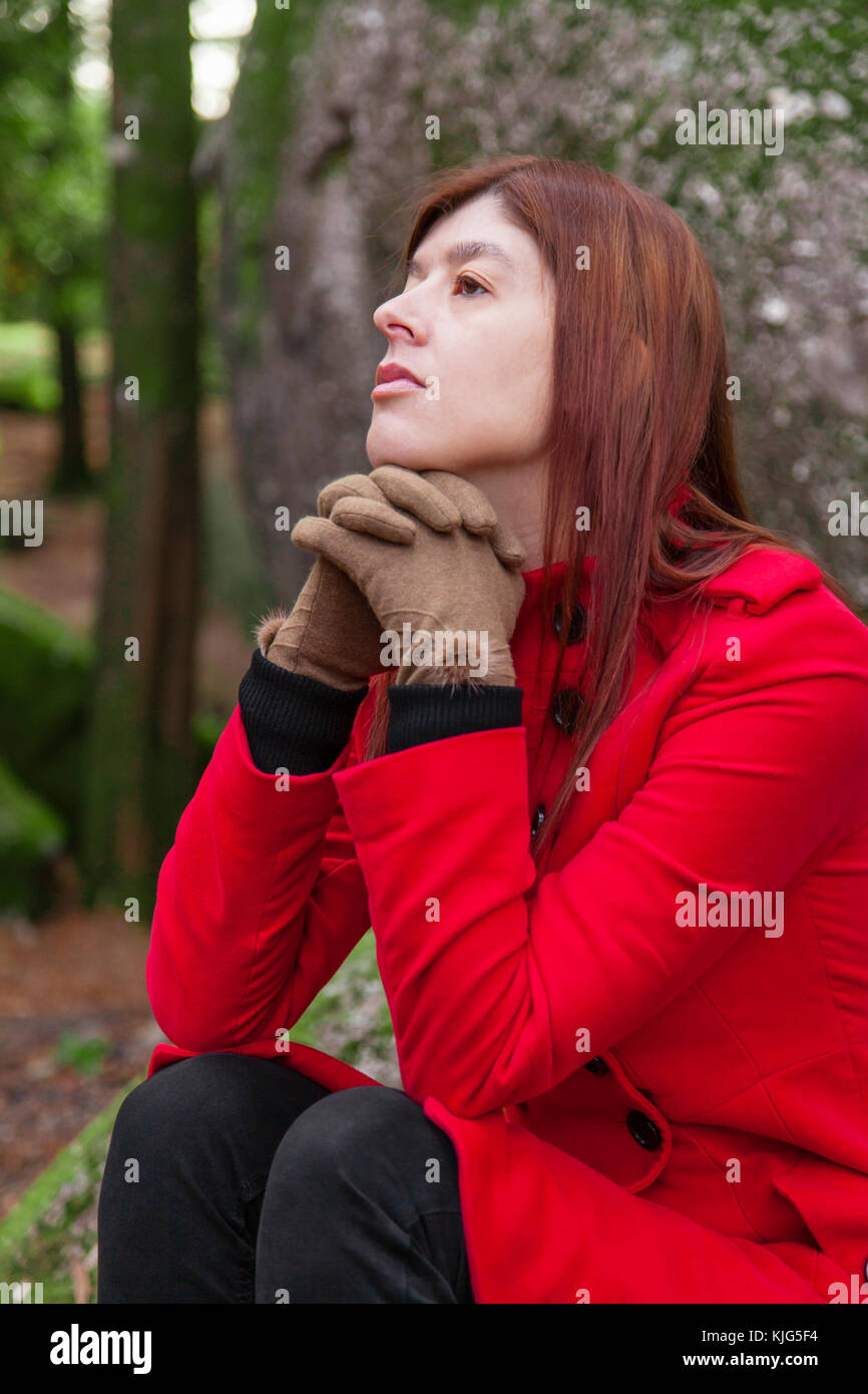 Jeune femme triste et déprimé dépression sentiment assis sur la forêt, à la recherche jusqu'à la pensée, mélancolique portant un long manteau ou pardessus pendant f Banque D'Images