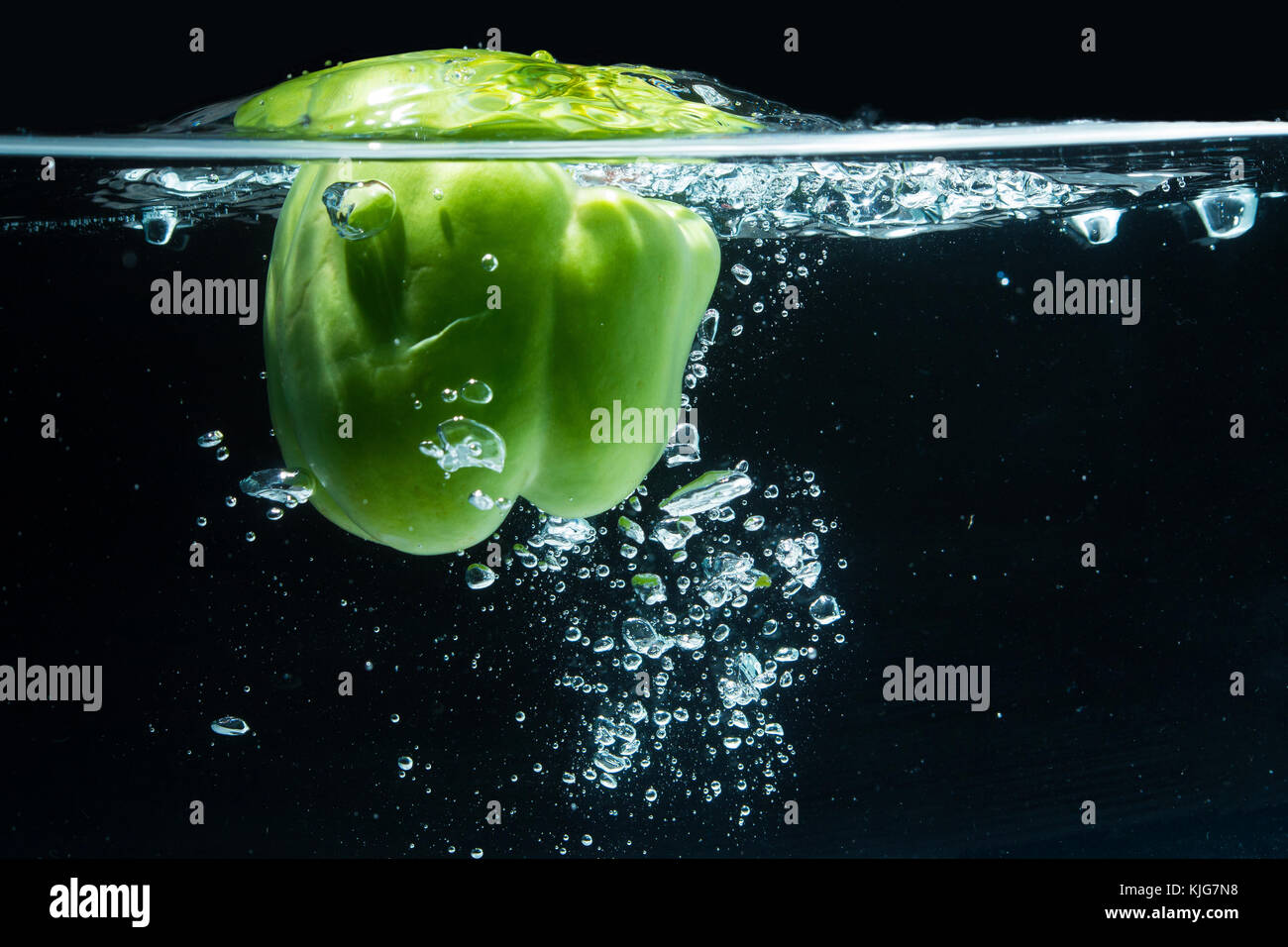 Poivron vert poussant dans l'eau, à la fois flexible surface tension une fraction d'un article avant qu'il perce Banque D'Images Poivron vert poussant dans l'eau, à la fois flexible surface tension une fraction d'un article avant qu'il perce Banque D'Images