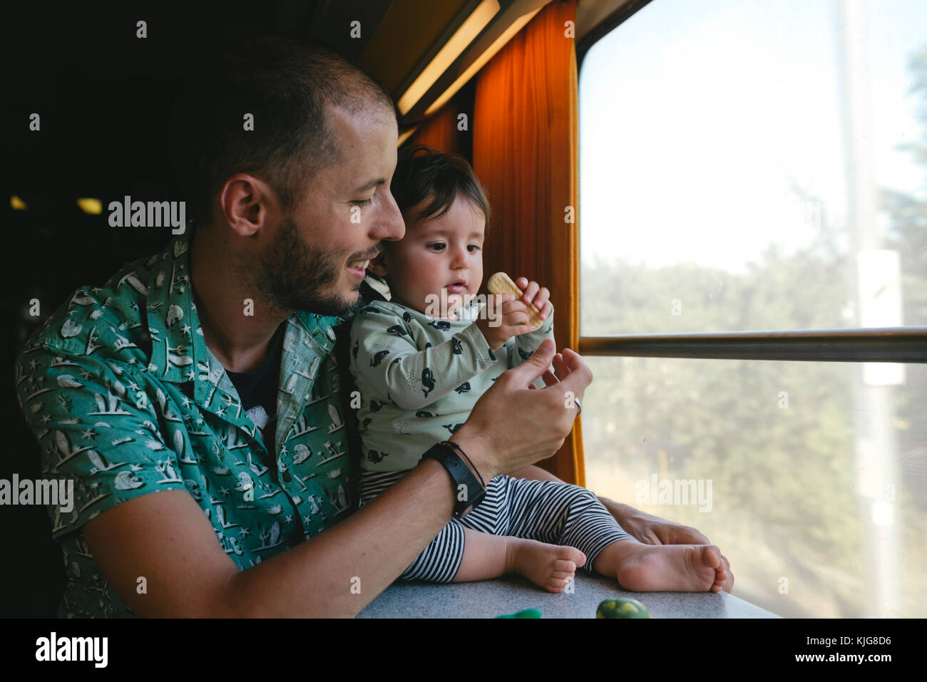 Père de donner un biscuit à sa fille pendant un voyage en train Banque D'Images