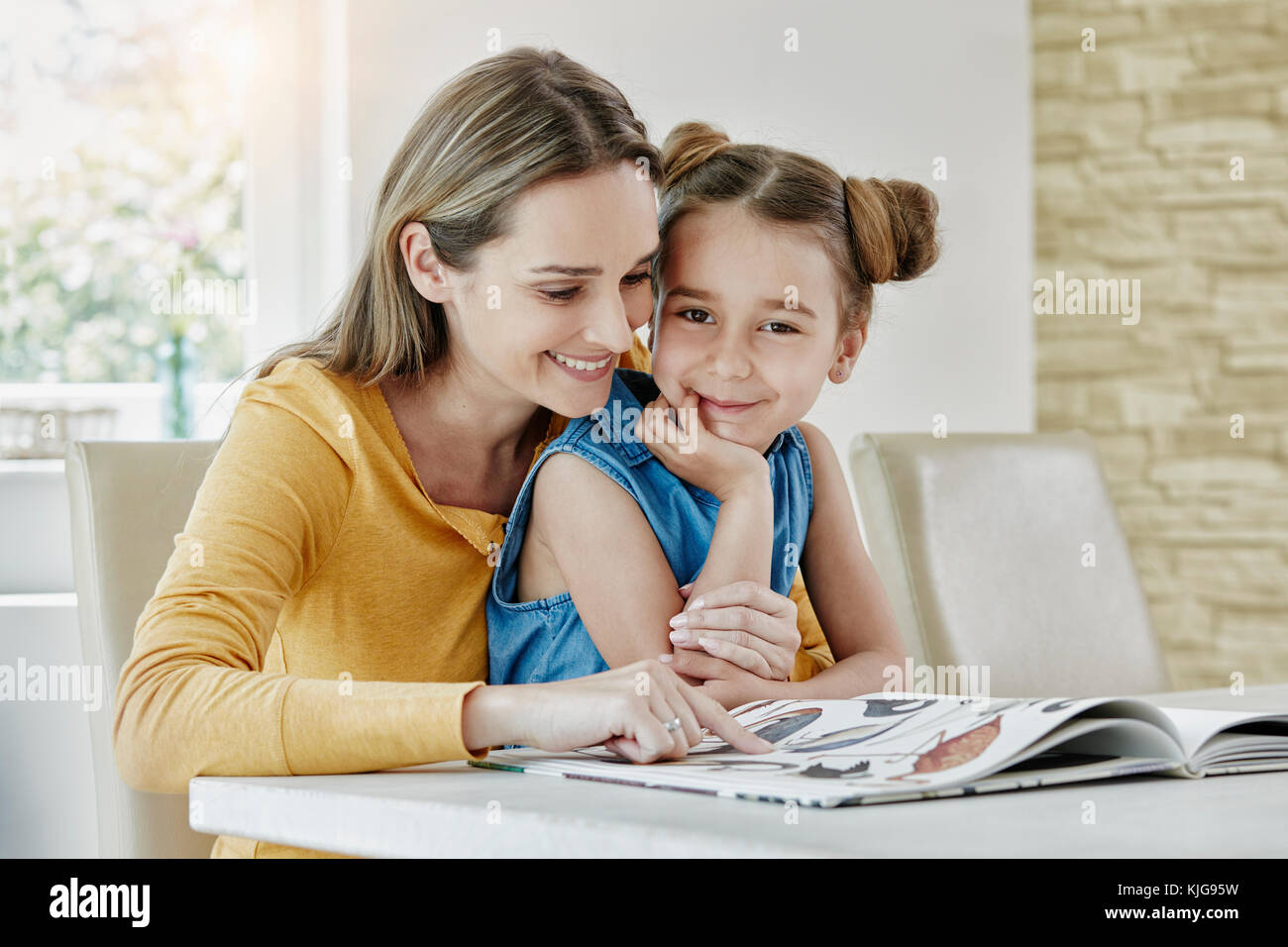 Mère heureuse avec sa fille à la maison à la recherche de photo book Banque D'Images