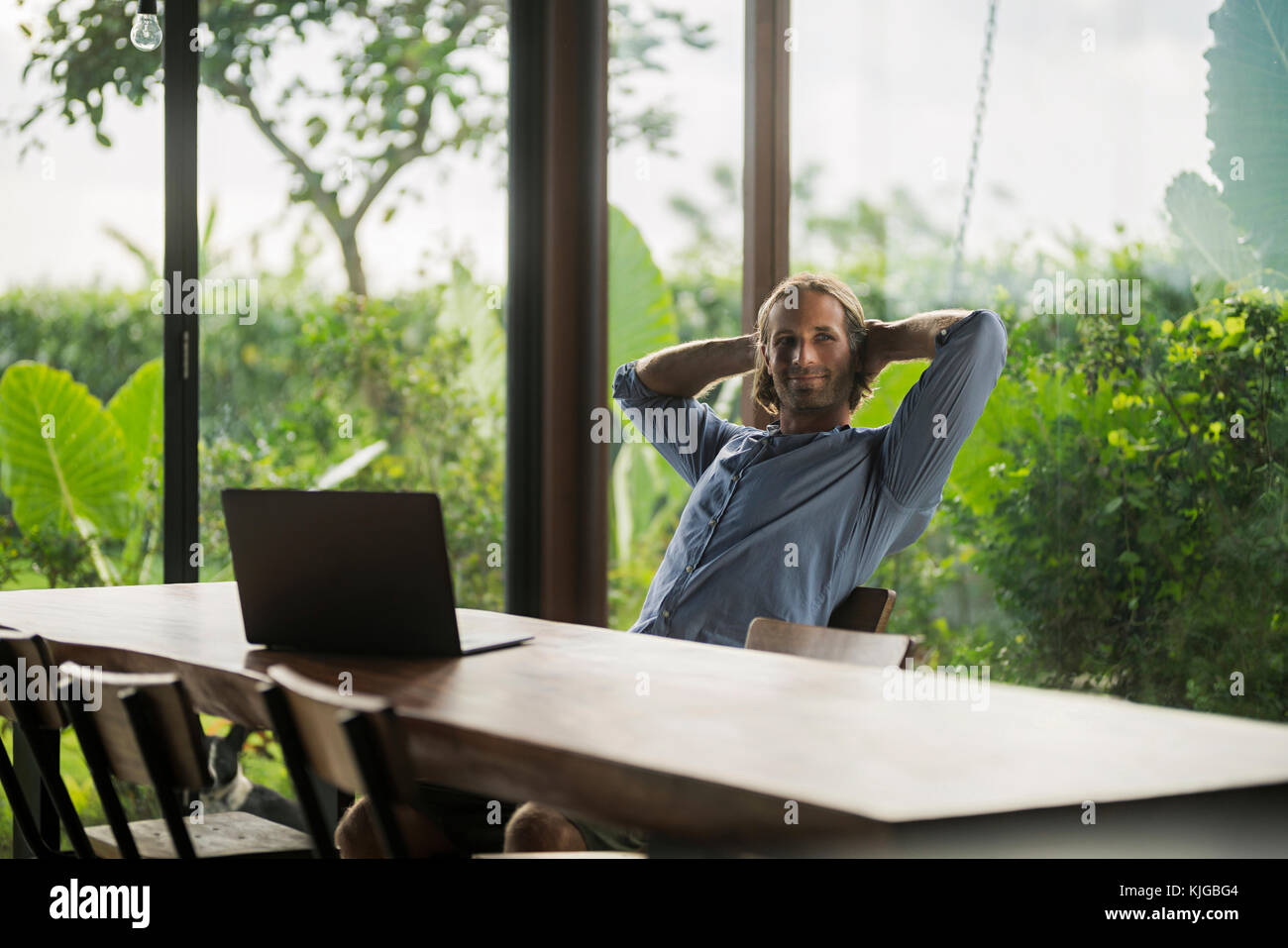 Handsome man with laptop sitting at table moderne en bois, de style moderne, chambre Banque D'Images