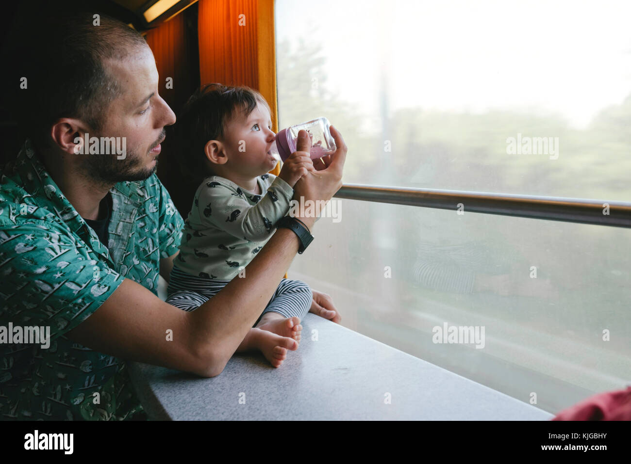 Donner de l'eau à son père fille bébé dans un biberon pendant un voyage en train Banque D'Images