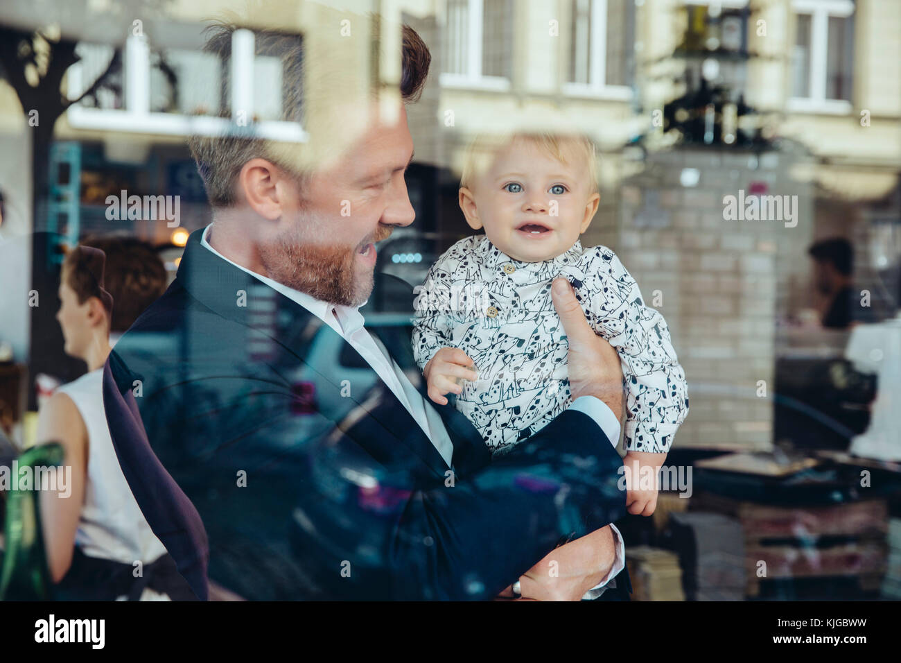 Businessman holding his baby boy in cafe Banque D'Images