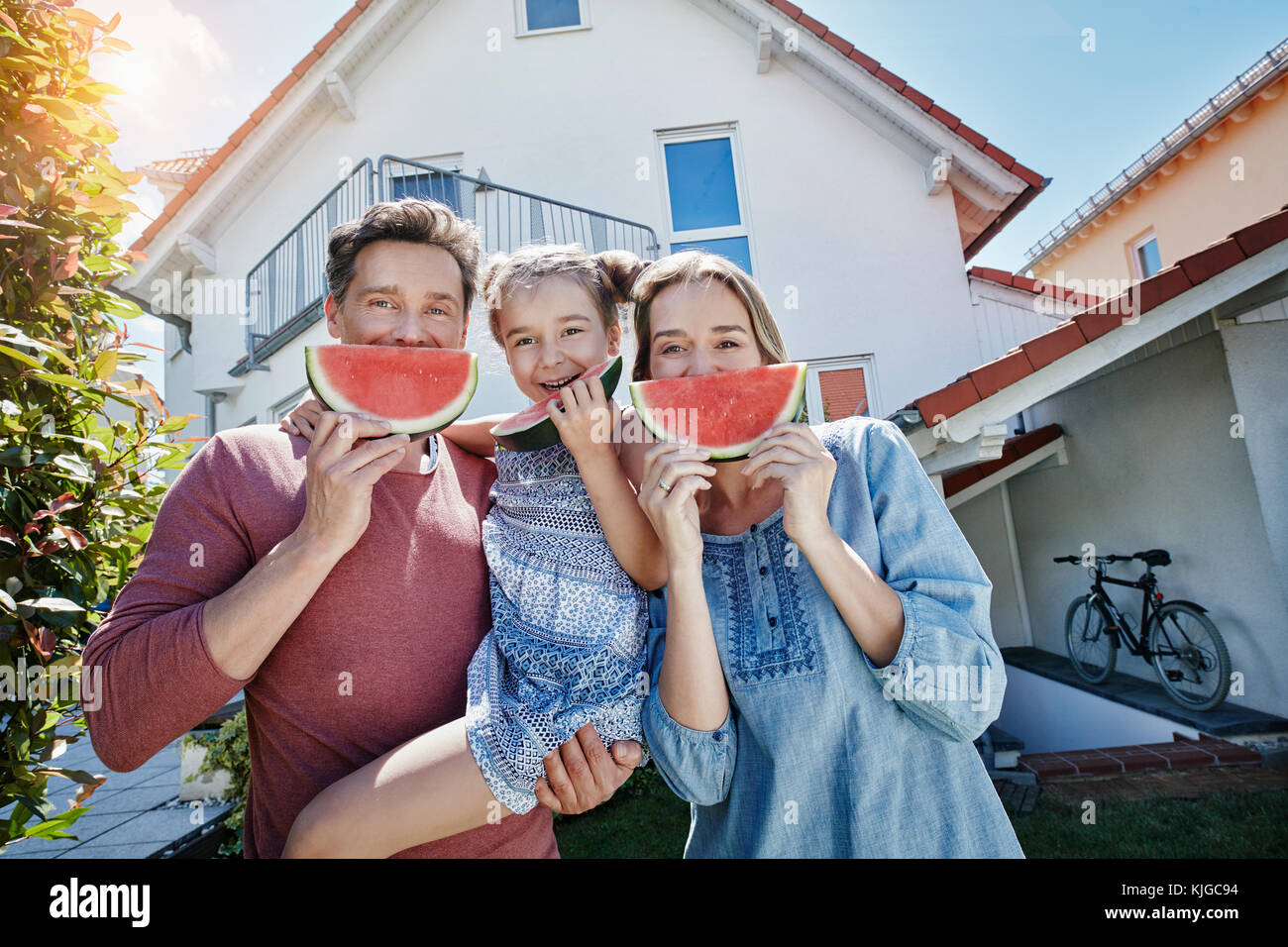 Portrait de famille heureuse avec des tranches de melon d'eau en face de leur maison Banque D'Images
