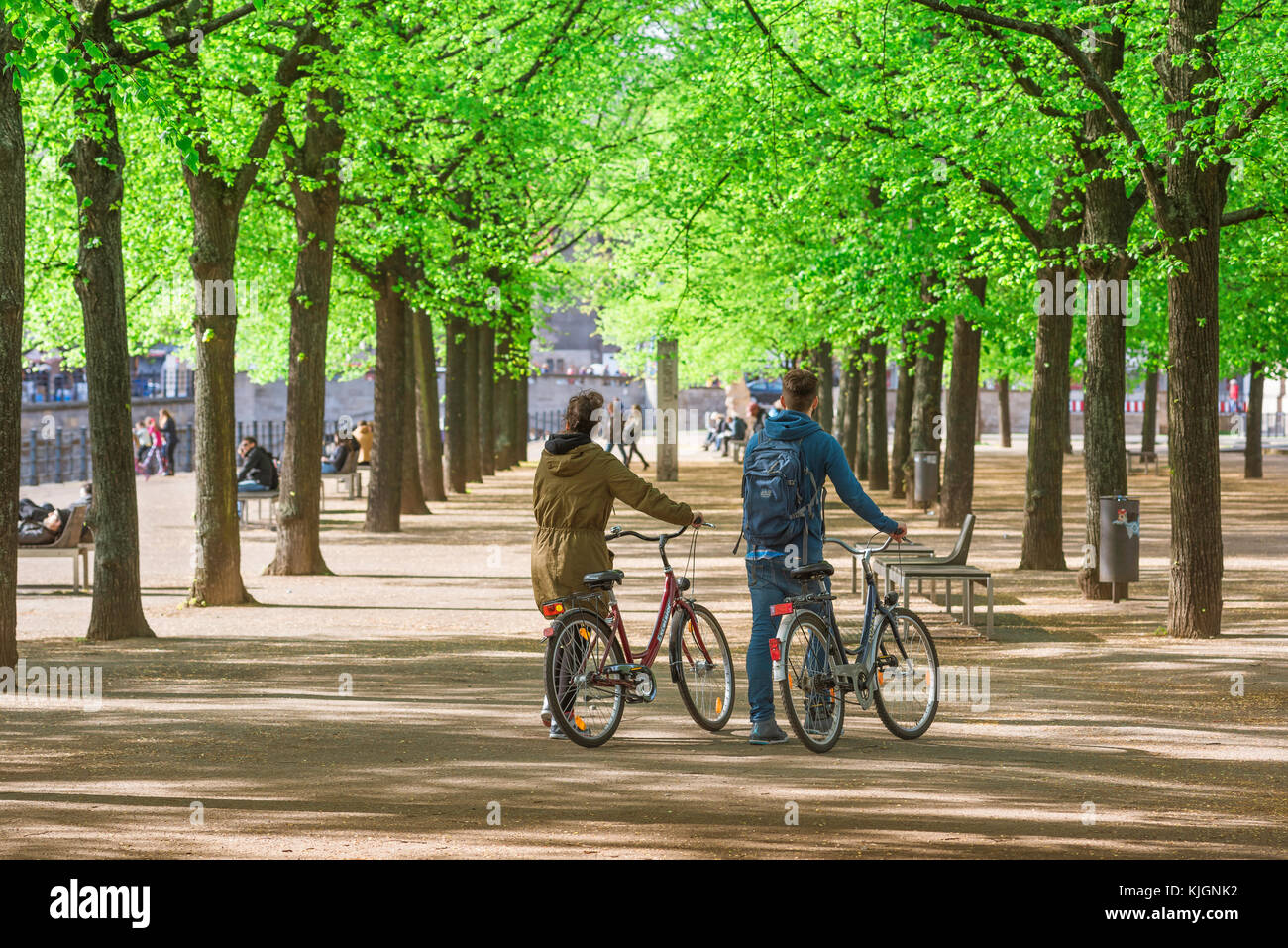 Les jeunes de Berlin, vue sur un après-midi de printemps tardif d'un jeune couple poussant leurs vélos dans le parc Lustgarten de Berlin, Allemagne. Banque D'Images