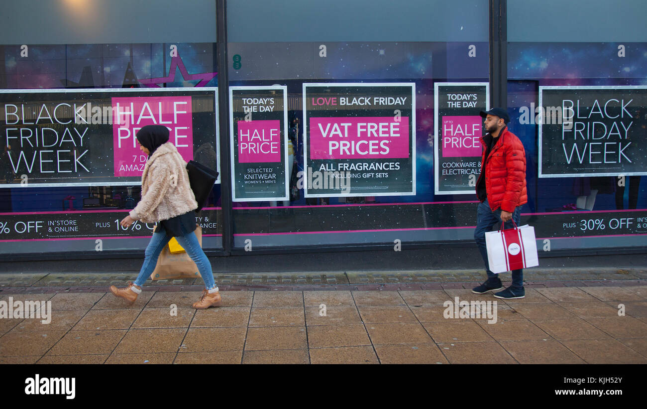 Les gens qui passent des vitrines des boutiques de mode au détail dans le centre-ville. Les clients dans le centre-ville, sur le Black Friday qui est devenu l'un des jours de shopping les plus importants de l'année. Les magasins de détail des offres de rabais et de réduire les prix dans une grande partie de leur stock pour démarre la saison des achats de cadeaux de Noël pour coïncider avec le chèque de paye de fin de mois. L'événement a commencé à prendre une compréhension bien libérale de 'Vendredi', cependant, avec de nombreux détaillants lançant les réductions jours avant ou même tout au long de la semaine précédente. Credit : MediaWorldImages/Alamy Live News Banque D'Images