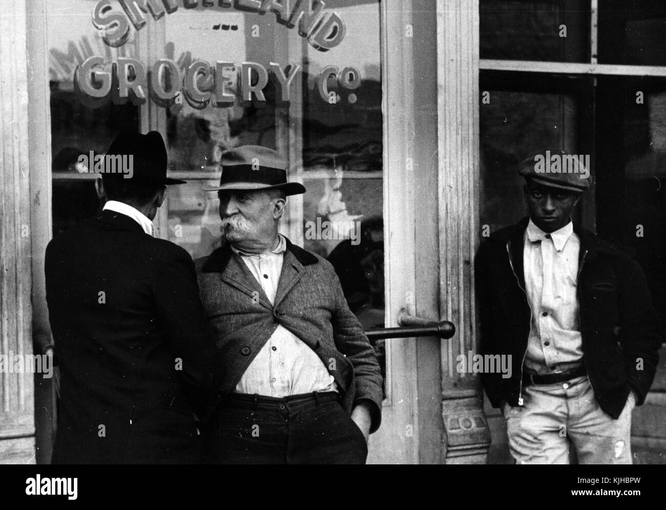 Photographie en noir et blanc de deux hommes blancs, et d'un homme afro-américain, debout devant une épicerie, par Ben Shahn, artiste américain d'origine lituanienne connu pour son travail pour la Farm Security Administration documentant les effets de la Grande dépression, Smithland, Kentucky, 1935. De la Bibliothèque publique de New York. Banque D'Images