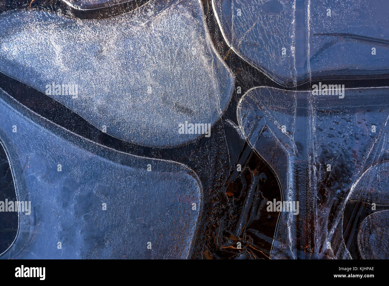 Beau fond d'hiver avec un motif d'une fine couche de glace sur une flaque d'eau dans la forme de formes différentes dans la lumière du soleil Banque D'Images