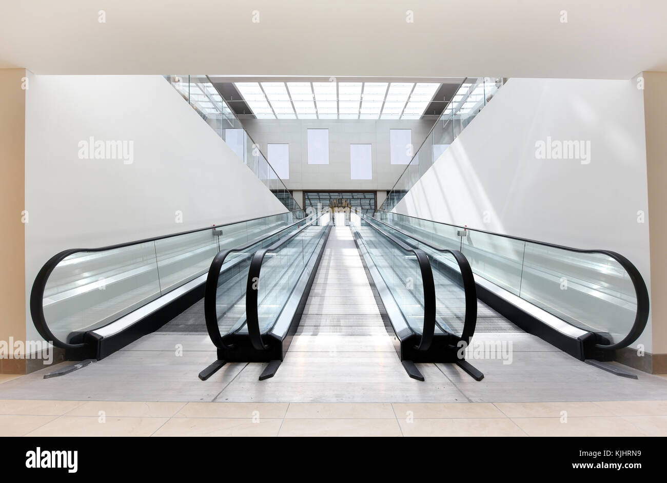 Deux escaliers mécaniques vides, l'un ascendant et un descendant, côte à côte dans un édifice commercial bien éclairées. Banque D'Images