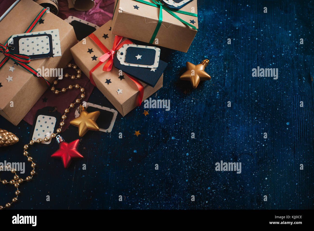 Décorations et gifts concept. fête de Noël dark flat fixer avec des boîtes en papier craft, étoiles, tags, de guirlandes et de copier l'espace sur une sombre w Banque D'Images