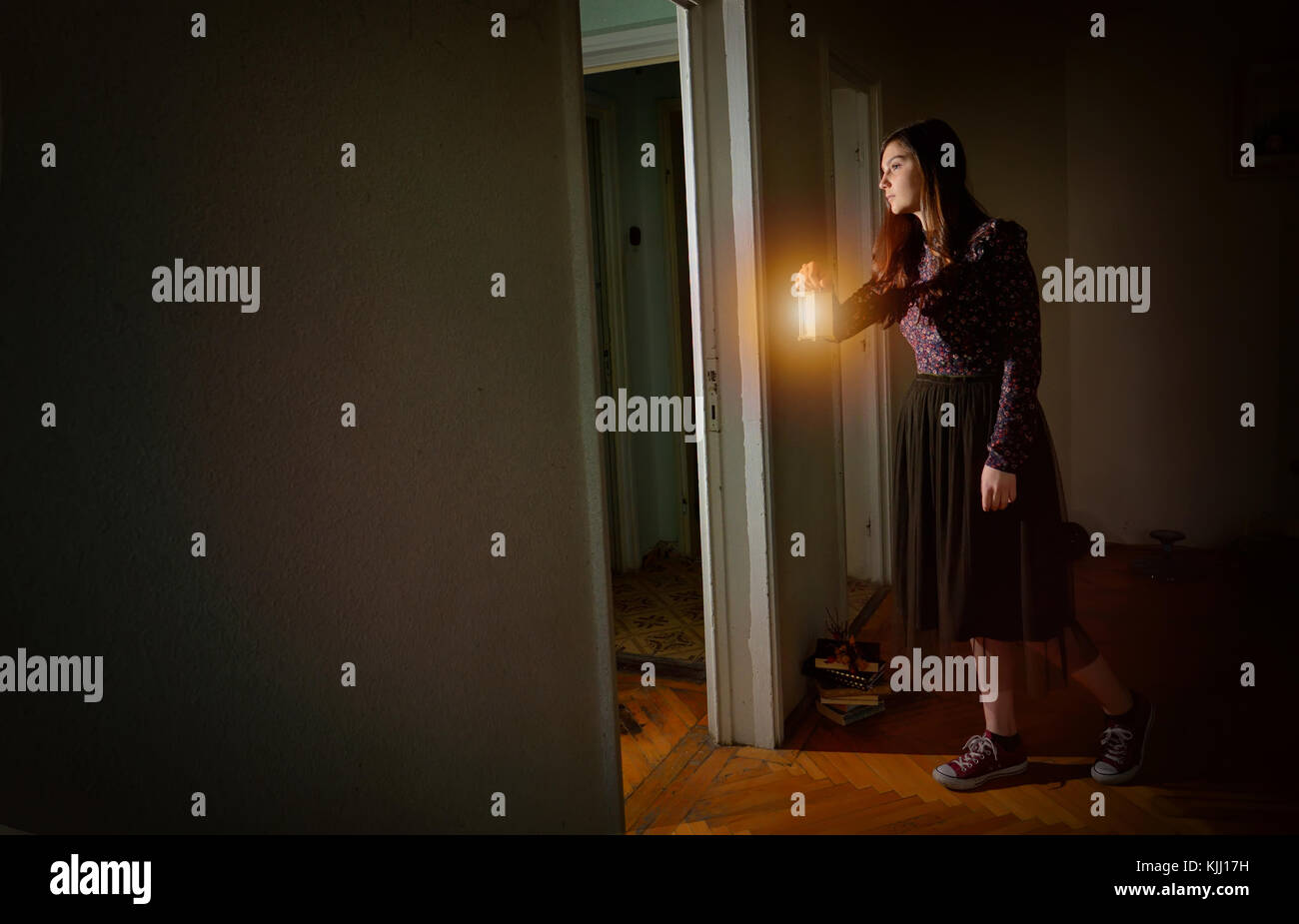 Jeune fille en robe vintage noire avec lanterne en maison vide Banque D'Images