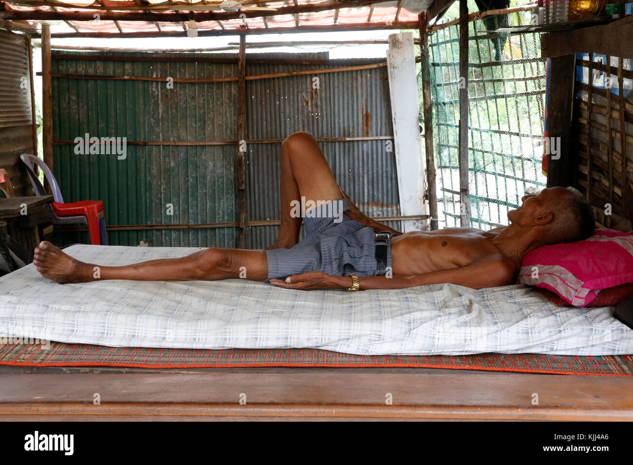 Vieil homme étendu sur son lit dans un bidonville. Battambang. Le Cambodge. Banque D'Images